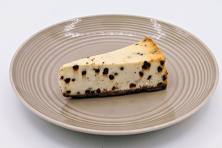 A rich slice of chocolate chip cheesecake on a chocolate cookie crust from Meal Village's fresh dessert delivery in Chicago.