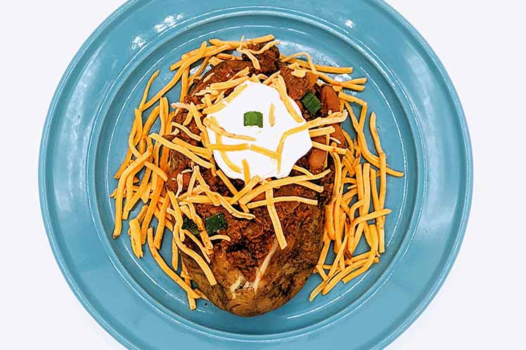 Baked potato bowl topped with beef chili, cheddar cheese and diced onions